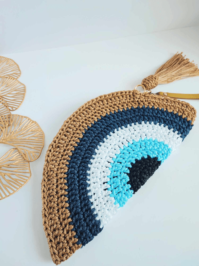 Sac Clutch mauvais œil fait main en crochet, pochette Nazar avec dragonne dorée, fermeture zippée et pompon – accessoire artisanal en polyester